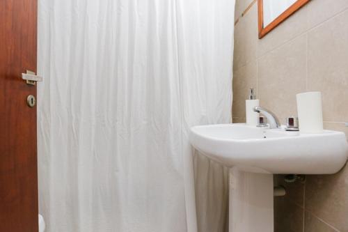 a bathroom with a sink and a white shower curtain at Candioti I Apartment - Santa Fe in Santa Fe