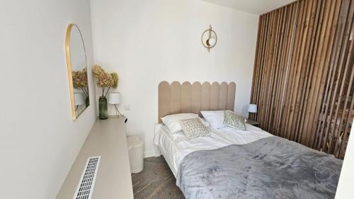 a white bedroom with a bed and a mirror at Apartament w Centrum 200 m od jeziora in Olecko
