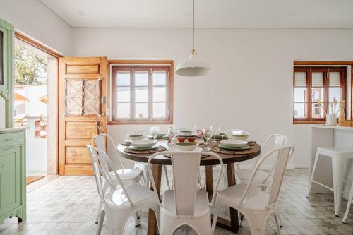 a dining room with a table and white chairs at Casa da Ti Maria Vieira in Santa Clara-a-Velha