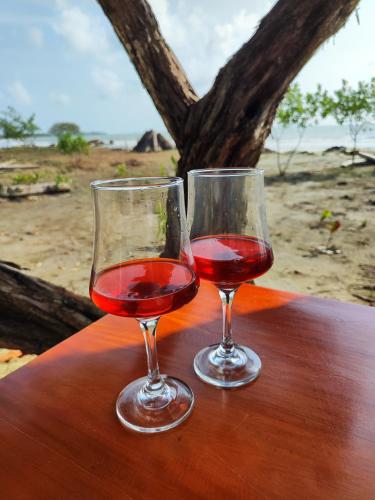 two glasses of red wine sitting on a wooden table at Casa Blanca Broqueles Hotel in Moñitos