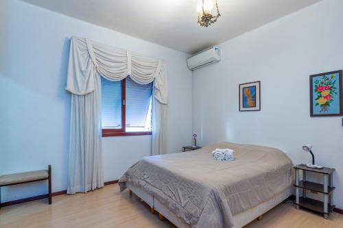 a bedroom with a large bed and a window at Casa 5 Quartos no Centro para 14 Pessoas in Gramado