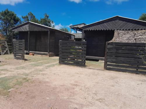 a couple of black buildings with brown roofs at Cabañas CARPE DIEM Con o sin jacuzzi in Barra del Chuy