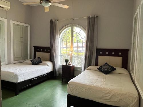 two beds in a room with a window at suites Casa Blanca in Ciudad Valles