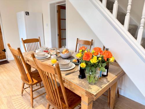 a dining room table with flowers in a vase at New Forest Cozy 3-Bed Family Cottage, PaultonsPark in Bartley