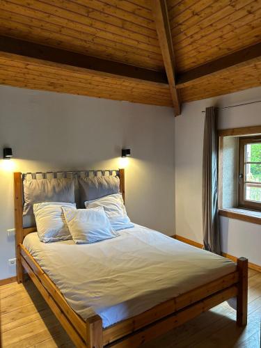 un grand lit dans une chambre avec un plafond en bois dans l'établissement Maison en pierre cosy avec piscine privé, à Dolmayrac