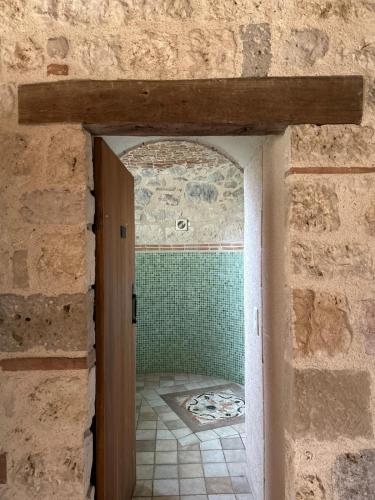 une porte donnant sur une salle de bain avec un mur en pierre dans l'établissement Maison en pierre cosy avec piscine privé, à Dolmayrac