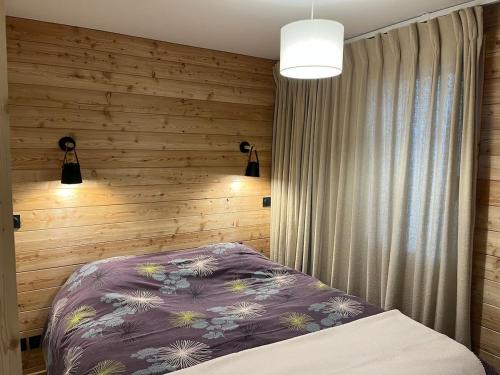 - une chambre avec un lit violet et un mur en bois dans l'établissement Résidence Albane, T3 entièrement refait, à Vars