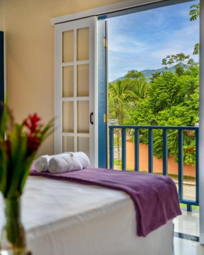 a bedroom with a balcony with a bed and a window at Casa Poema Paraty in Paraty