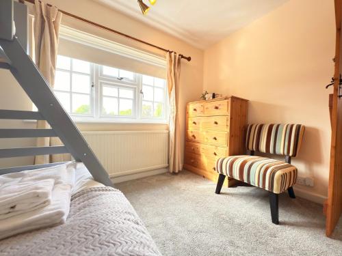 a bedroom with a bed and a chair and a window at New Forest Cozy 3-Bed Family Cottage, PaultonsPark in Bartley