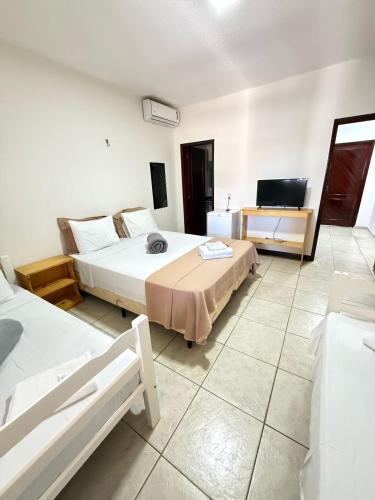 a bedroom with two beds and a television in it at Milano Hotel Pousada Canoa Quebrada in Canoa Quebrada