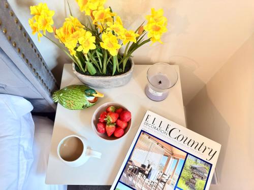 a table with a book and a cup of coffee and flowers at New Forest Cozy 3-Bed Family Cottage, PaultonsPark in Bartley