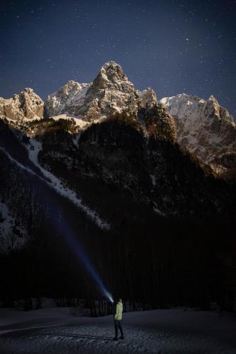 a person standing in the snow at night with a mountain at ETHNO STAR Bojović in Gusinje