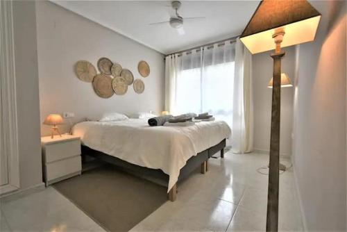 Un dormitorio con una cama y una lámpara y una ventana. en Casa Ra Sol, en Orihuela Costa