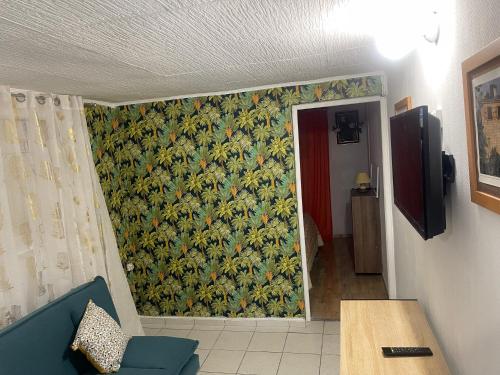 a living room with a wall with a floral wallpaper at Gîte youyoute in Bouillante