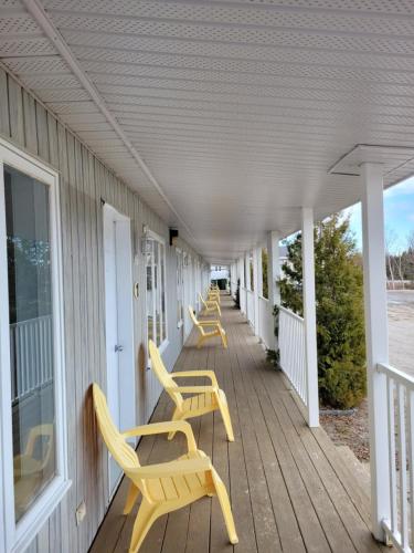 a row of yellow chairs on the porch of a house at Motel La Croisière in Grandes-Bergeronnes