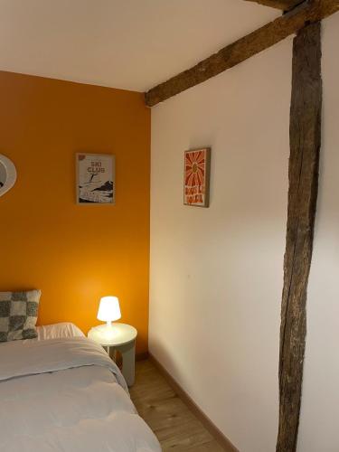 - une chambre avec des murs orange, un lit et une lampe dans l'établissement Appartement charmant, à Tournay