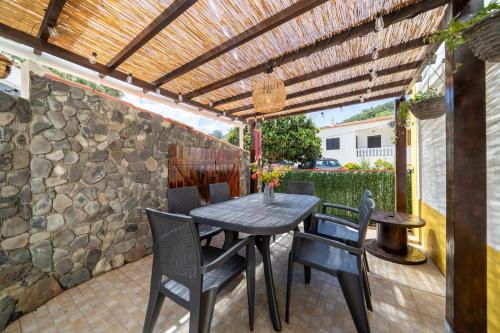 a patio with a table and chairs under a wooden pergola at Casa do Sol in Bordeira