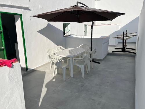 ein Tisch und Stühle mit einem Sonnenschirm auf einer Terrasse in der Unterkunft Casa Ianira in El Puerto de Santa María
