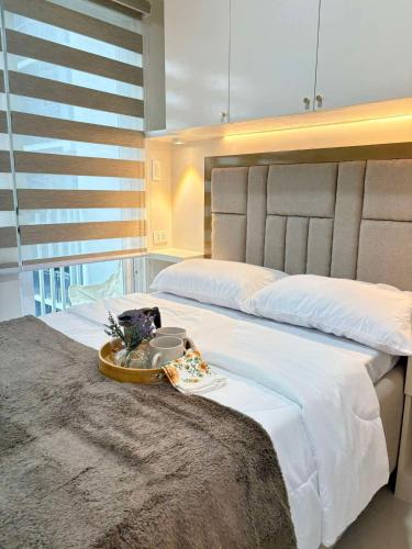 a bedroom with a large bed with a tray on it at RJ Elite Escape 2BR Condo w balcony near SM Iloilo in Iloilo City