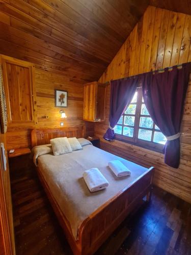 una camera con un grande letto in una cabina di Cabañas La Ponderosa a Villa Ventana