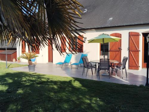 un patio avec une table, des chaises et un parasol dans l'établissement Villa évasion, à Ambillou