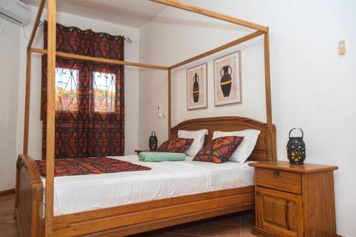 a bedroom with a wooden canopy bed with pillows at Charming Vacation House in Ngaparou