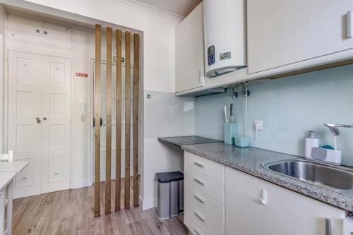 een keuken met witte kasten en een spoelbak bij Graça Garden Home in Lissabon