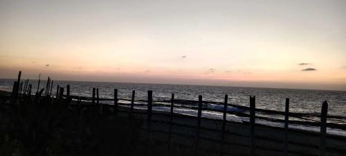 a fence on the beach near the ocean at sunset at SECLUDED GLAMPING YOGA SAMADHI fan 2 kubos 8 pax in Rimus