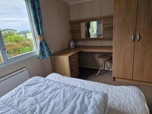 a bedroom with a bed and a desk and a window at The Lookout 3 Bedroom Family Caravan with Sea View Pet Friendly in Aberystwyth