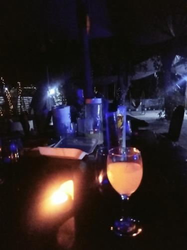 a glass of wine sitting on a table with a candle at SECLUDED GLAMPING YOGA SAMADHI fan 2 kubos 8 pax in Rimus