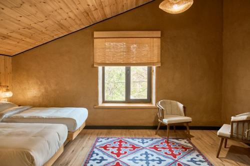 a bedroom with two beds and a window and a chair at Pristine Hotel in Bishkek