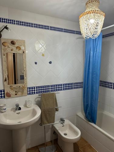 a bathroom with a sink and a toilet and a mirror at Beach Apartment in Huelva