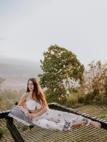 a woman sitting on a blanket on a bench at Copoazú Glamping in Floridablanca