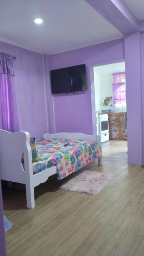 a purple bedroom with a bed and a tv at Saint George's Romantic Getaway Suite in Mount Gay