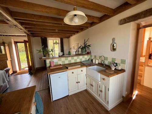 Il comprend une cuisine avec des placards blancs et du parquet. dans l'établissement Chalet des Roches Roche d'Oëtre Suisse Normande, à Saint-Philbert-sur-Orne