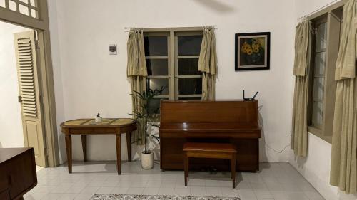a living room with a piano and a table at Kosasih 1919 A Dutch-Retro House in Banyuwangi