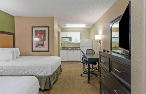 a hotel room with a bed and a desk with a television at Extended Stay America Suites - Louisville - Dutchman in Louisville