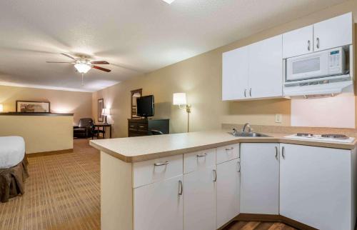 a kitchen with white cabinets and a living room at Extended Stay America Suites - South Bend - Mishawaka - North in South Bend
