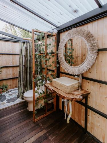 a bathroom with a toilet and a mirror on a deck at Copoazú Glamping in Floridablanca