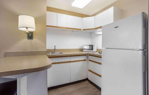 a small kitchen with white cabinets and a refrigerator at Extended Stay America Suites - Meadowlands - East Rutherford in East Rutherford