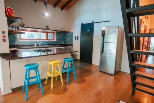 a kitchen with blue and yellow stools and a refrigerator at Casa BuenaOnda Asunción in Asuncion