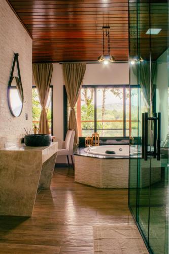 a bathroom with a tub and a large window at Pousada Paraíso das Araucárias Monte Verde Vista das montanhas in Monte Verde