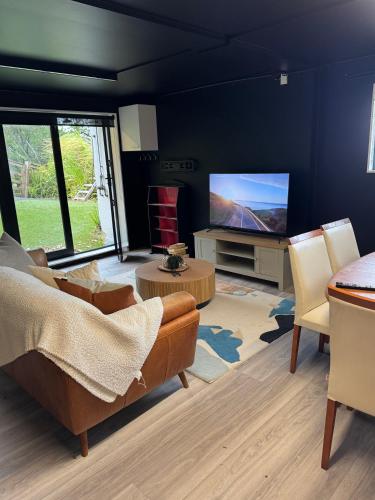 a living room with a couch and a flat screen tv at Sandy Toes & Netflix Nights, Relaxing Auckland Retreat in Auckland