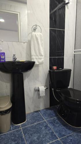 a bathroom with a black toilet and a sink at Hotel Valle del Café - Habitación 8 Grupo 2 Camas in Sevilla