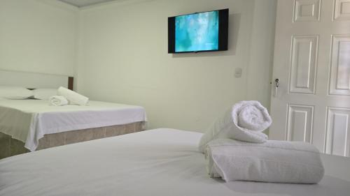 a room with two beds and a towel chair at Hotel Valle del Café - Habitación 8 Grupo 2 Camas in Sevilla