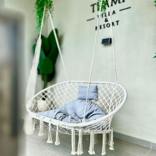 a white hanging chair with a pillow in a room at Tijami Villa & Resort in Kampong Mangkok