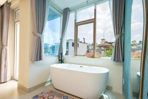 a bathroom with a large white tub in front of a window at Hoshi Apartment in Ho Chi Minh City