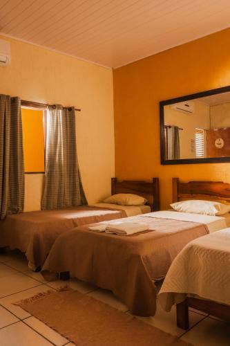 a bedroom with two beds and a mirror at Pousada Refugio Prumirim in Ubatuba