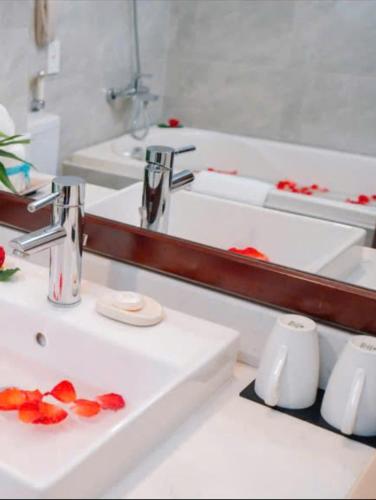 a bathroom with two sinks and a mirror and red flowers at Muong Thanh Grand Phuong Dong in Vinh