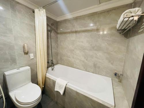 a bathroom with a toilet and a bath tub at Muong Thanh Grand Phuong Dong in Vinh